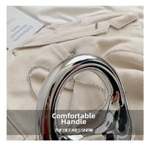 Detail view of the silver liquid metal acrylic bag with a sleek chain on a blazer