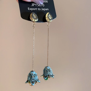 Macro view of vintage gold-plated tassel earrings with blue flower buds and crystals