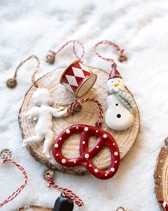 Detailed view of ceramic angel, snowman, and drum ornaments on a rustic wood slice