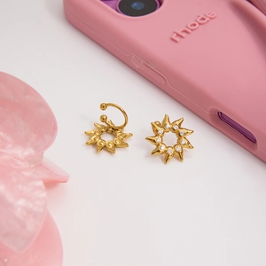 Vue macro d'un earcuff soleil doré 18K et boucle d'oreille sertis de strass brillants