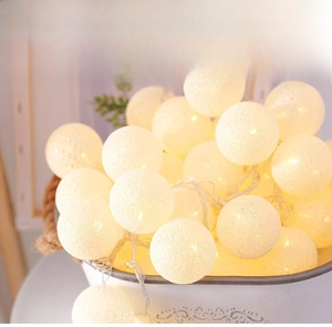 Detail of warm white cotton ball LED fairy lights stacked in a vintage metal bucket