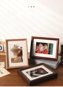 Detail of wooden picture frames in various wood tones with white mats on a desk