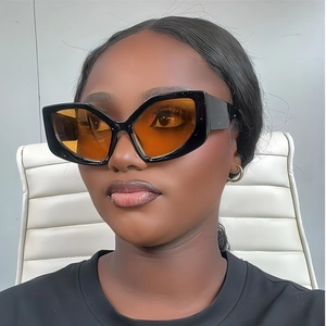 Front view of model wearing oversized geometric sunglasses with orange tinted lenses