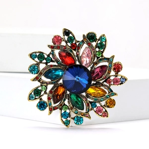 Vintage floral alloy brooch with colorful rhinestones on a white geometric stand