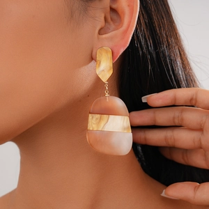 Detail view of oval acetate geometric earrings in amber and marble tones on model
