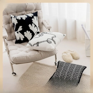 Close-up of beige and black jacquard cushion covers with chenille texture and leaf patterns