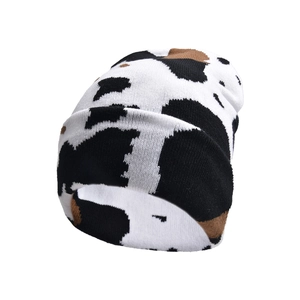 Winter knitted beanie with black white and brown cow print pattern in street style
