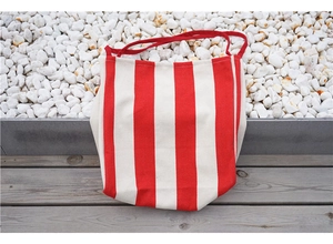 Close-up of classic red and cream vertical striped canvas tote bag on wooden floor