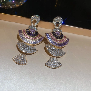 Macro shot of fan-shaped fan-shaped drop earrings with purple and pink crystals in gold