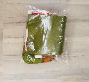 Gros plan d'un lutin de Noël en feutrine rouge et verte, emballé dans un sac en plastique