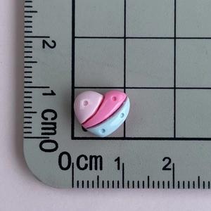Close-up of tricolor resin heart charms showing size on a centimeter scale ruler