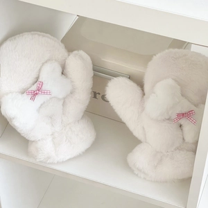 Dettaglio di muffole in peluche crema con fiocco a scacchi rosa e morbida ecopelliccia