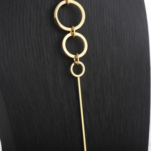 Detail of gold geometric necklace featuring triple rings and a long sleek metal bar pendant