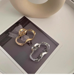 Detail of irregular wave liquid metal hair claws in glossy gold and silver finishes