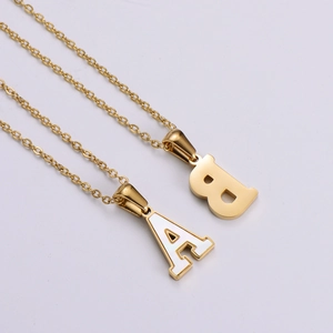 Detail of 18k gold plated alphabet pendants with white shell inlay on a fine chain