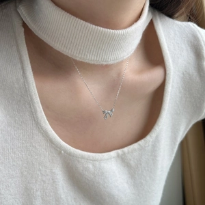 Elegant S925 silver bow pendant necklace with sparkling diamonds worn by a model