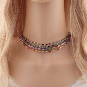 Close-up of multilayered gold necklace featuring vibrant colorful square crystal gemstones