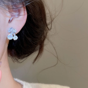 Close-up of a zircon cherry stud earring worn by a model in warm elegant lighting