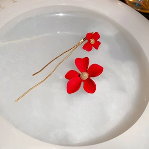 Detail of asymmetric red heart-petal flower earrings with gold tassels and center beads