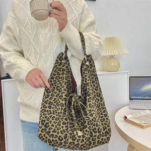 Close-up of leopard print canvas tote bag with oval metal tag and drawstring detail