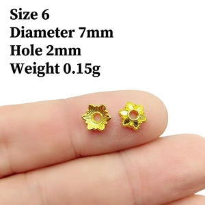 Detailed view of 7mm gold hollow flower bead cap spacers on a fingertip for DIY jewelry