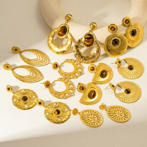 Bohemian vintage gold plated earrings set with natural stones and pearls on white pedestals