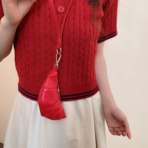 Détail macro du mini sac croissant rouge en cuir brillant avec un fermoir en métal