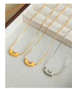Détail de pendentifs en forme de U dorés et argentés sur des chaînes serpent élégantes