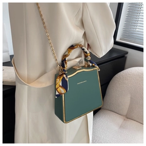 Detailed side view of a green mini square bag with gold chain and scarf handle