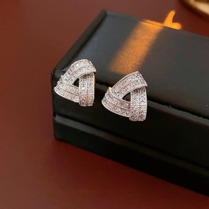 Vue latérale macro de boucles d'oreilles triangle en zircon sur boîte à bijoux en cuir