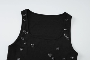 Dettaglio di perle di cristallo sullo scollo di un abito nero in maglia a coste