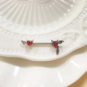 Silver devil bat nipple ring with red heart zircons and winged tail on white ceramic