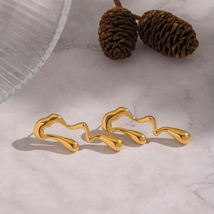 Gros plan de boucles d'oreilles dorées irrégulières sur un fond de marbre