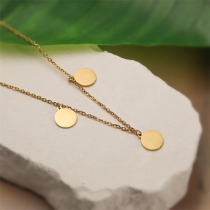 Detailed view of three circular gold-finished pendants on a thin stainless steel necklace