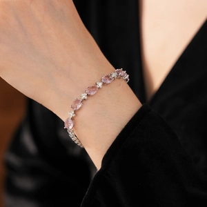 Detail of a silver floral bracelet featuring pink oval zircons on a model's wrist