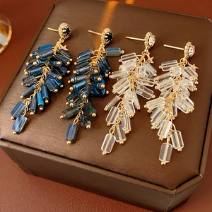 Detail of long tassel earrings with crystal beads and gold stars in blue and white