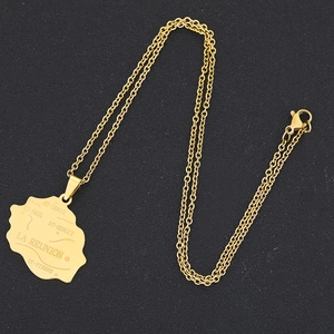 Macro shot of gold stainless steel La Réunion island map pendant with engraved city names