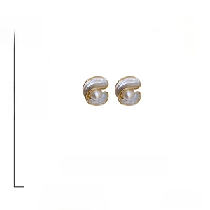 Detailed view of geometric shell earrings with faux pearls and 925 silver needles