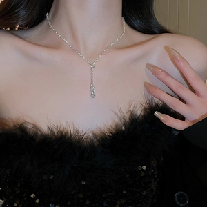 Détail d'un collier en Y argenté orné de cristaux étincelants sur un mannequin