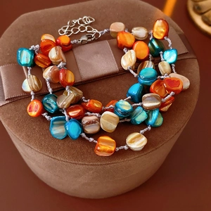 Detailed close-up of bohemian layered shell bead bracelet with colorful irregular stones