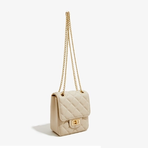 Detail of beige quilted PU leather crossbody bag with metal chain strap and twist lock clasp