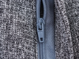 Detailed close-up of the smooth blue-grey zipper and textured tweed fabric of the suit