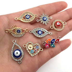 Detailed view of various Evil Eye charms and connectors held in hand for DIY jewelry making