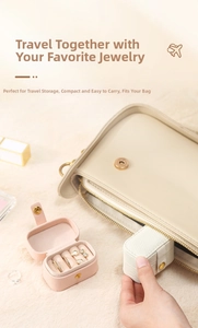 Mini leather travel jewelry box with metal clasp being placed into a handbag