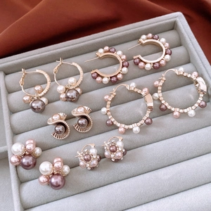 Macro detail of various pearl earrings featuring white and mocha pearls on gold alloy