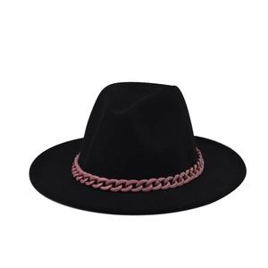 Détail d'un chapeau fedora en feutre noir avec une grosse chaîne décorative rose mat