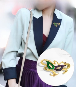 Close-up of green and purple enamel mask brooch with rhinestones on a blazer