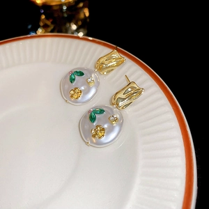 Macro detail of French vintage floral earrings with resin green leaves and gold petals