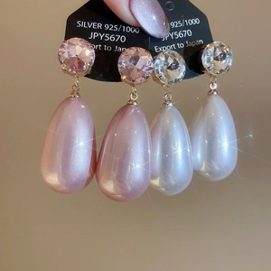 Macro detail of elegant teardrop pearl earrings with S925 silver studs and crystals
