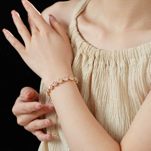Detailed view of pink heart zircon bracelet on wrist with adjustable gold slider clasp
